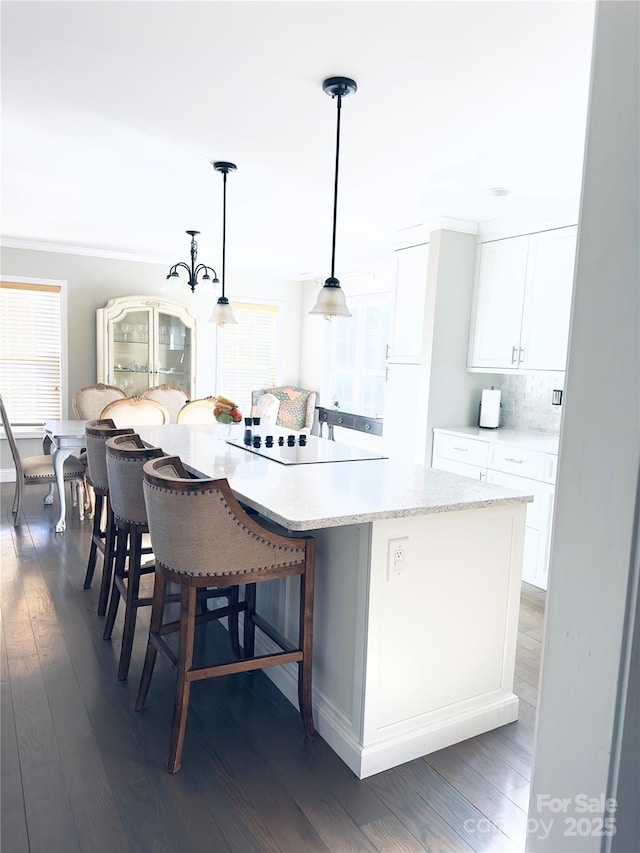 kitchen featuring dark hardwood / wood-style flooring, decorative light fixtures, white cabinets, and a kitchen island