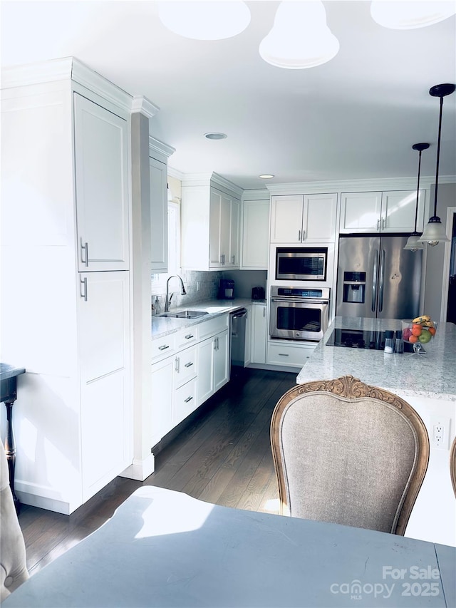 kitchen featuring sink, hanging light fixtures, dark hardwood / wood-style floors, stainless steel appliances, and light stone countertops