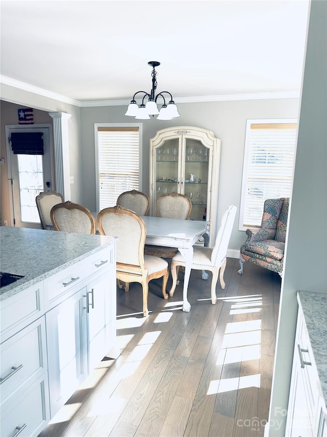 dining area with an inviting chandelier, crown molding, and light hardwood / wood-style flooring