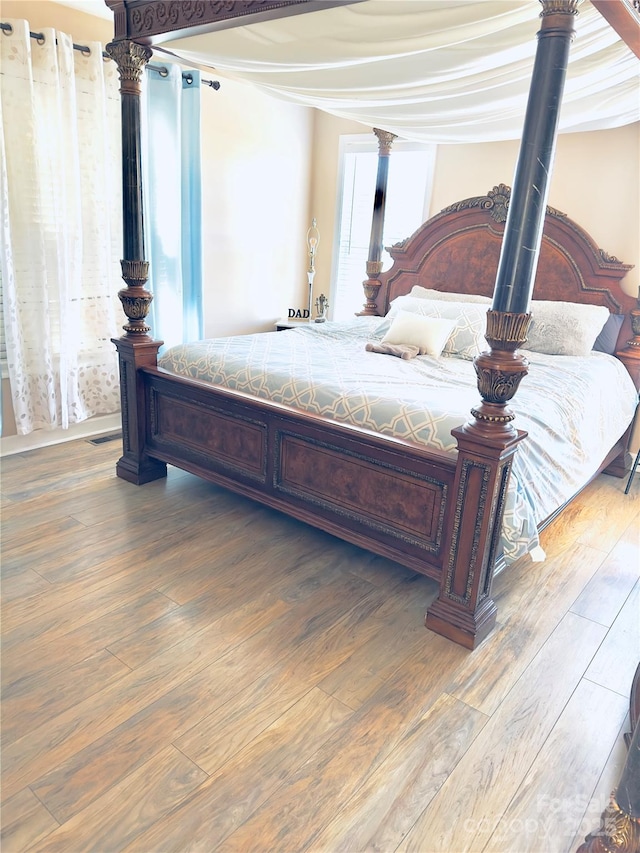 bedroom with decorative columns and wood-type flooring