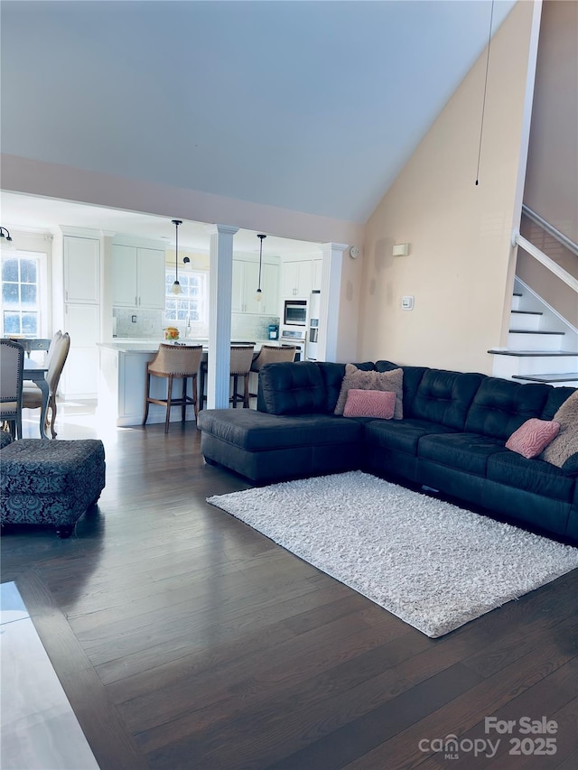 living room featuring high vaulted ceiling and dark hardwood / wood-style floors