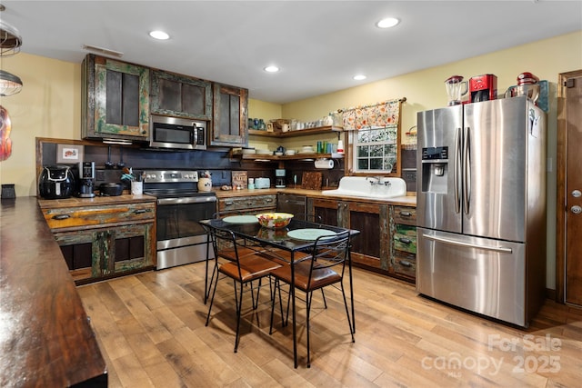 kitchen with sink, dark brown cabinets, stainless steel appliances, and light wood-type flooring