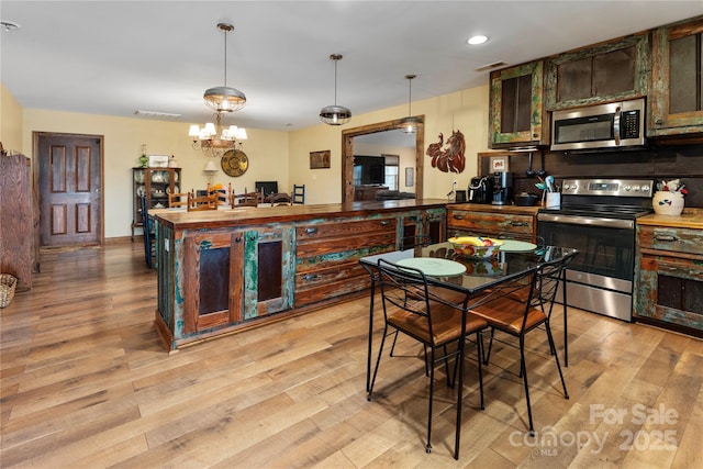 kitchen with pendant lighting, light hardwood / wood-style flooring, stainless steel appliances, and dark brown cabinetry