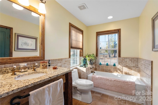 bathroom featuring tile walls, vanity, toilet, and a tub to relax in