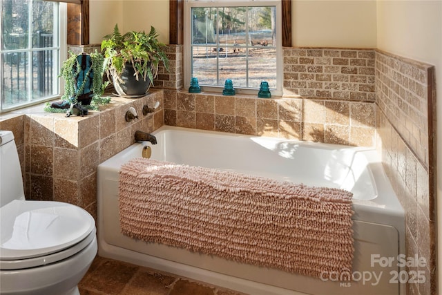 bathroom featuring a bath, a wealth of natural light, and toilet