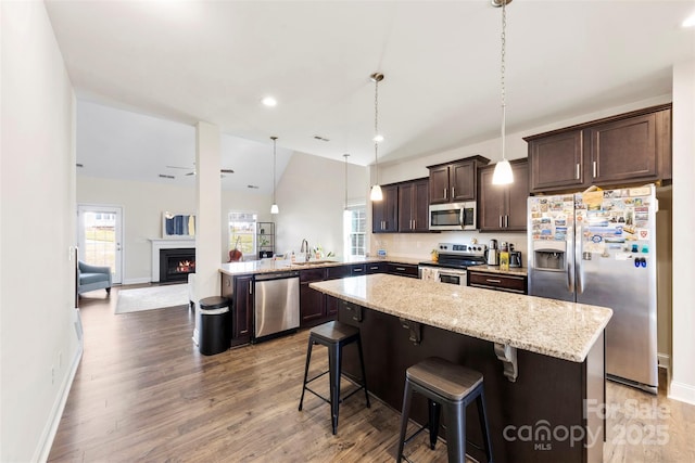 kitchen featuring sink, a breakfast bar area, appliances with stainless steel finishes, hanging light fixtures, and kitchen peninsula