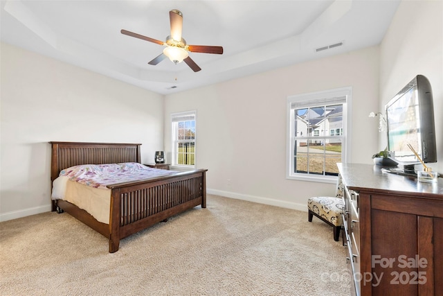 bedroom featuring a raised ceiling, light carpet, and ceiling fan