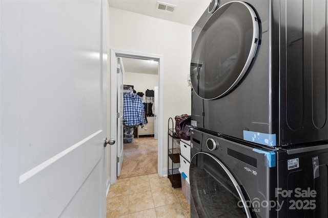 washroom featuring light tile patterned flooring and stacked washer / dryer