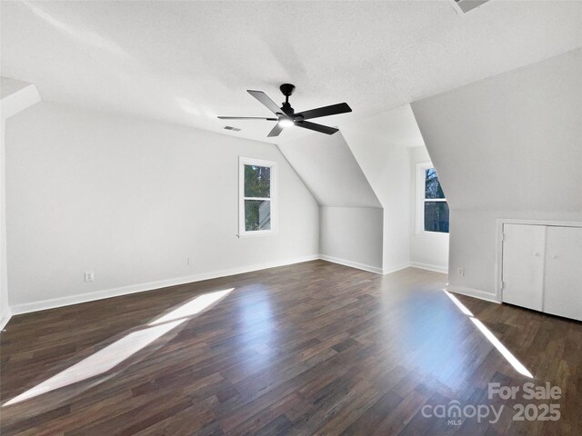 additional living space with ceiling fan, dark hardwood / wood-style floors, vaulted ceiling, and a textured ceiling