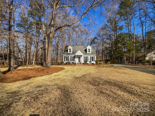 cape cod home with covered porch and a front lawn