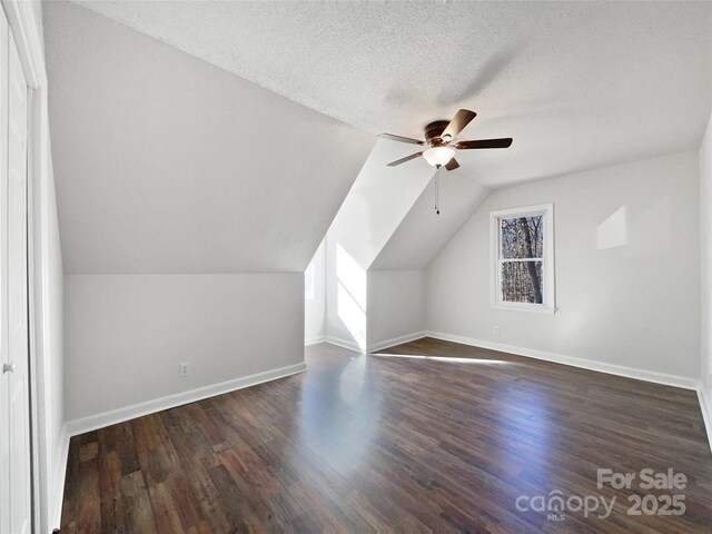 additional living space with vaulted ceiling, dark hardwood / wood-style floors, ceiling fan, and a textured ceiling