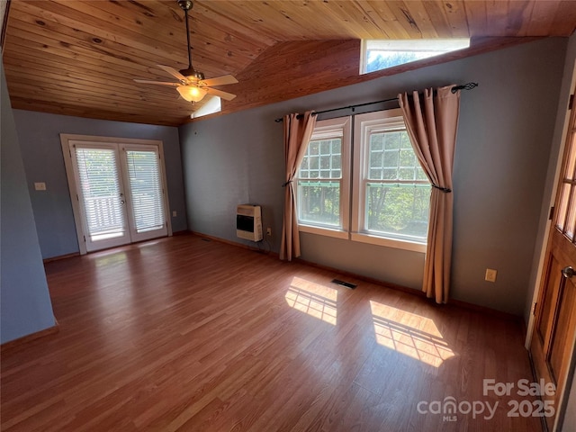 empty room with lofted ceiling, wood ceiling, ceiling fan, heating unit, and light hardwood / wood-style floors