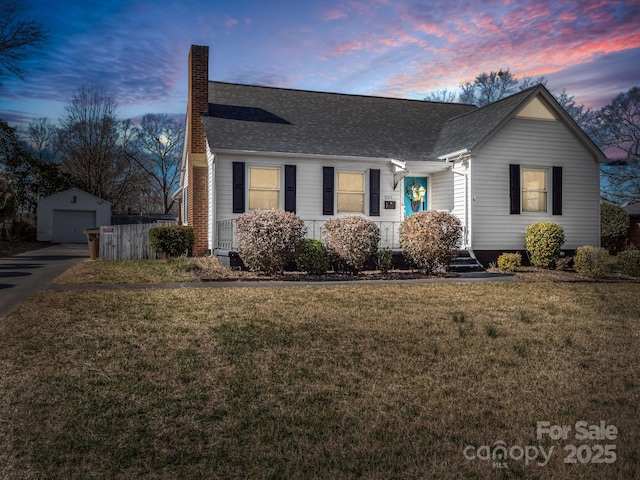 single story home with an outbuilding, a garage, and a lawn