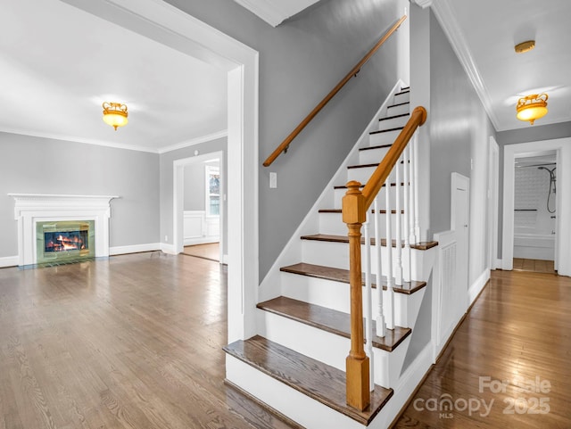 staircase with ornamental molding and hardwood / wood-style floors