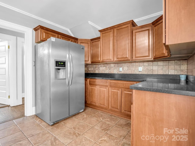 kitchen featuring tasteful backsplash, vaulted ceiling, light tile patterned floors, and stainless steel fridge