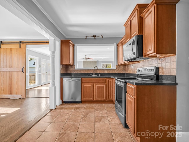 kitchen featuring sink, crown molding, tasteful backsplash, light tile patterned floors, and stainless steel appliances