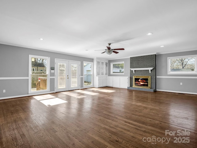 unfurnished living room with dark hardwood / wood-style flooring, a fireplace, ornamental molding, and a healthy amount of sunlight