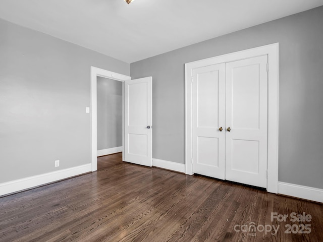 unfurnished bedroom featuring dark wood-type flooring and a closet