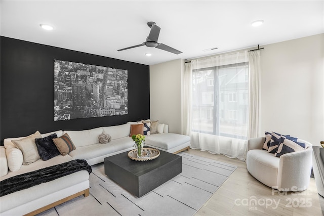 living room with light wood-style floors, ceiling fan, visible vents, and recessed lighting