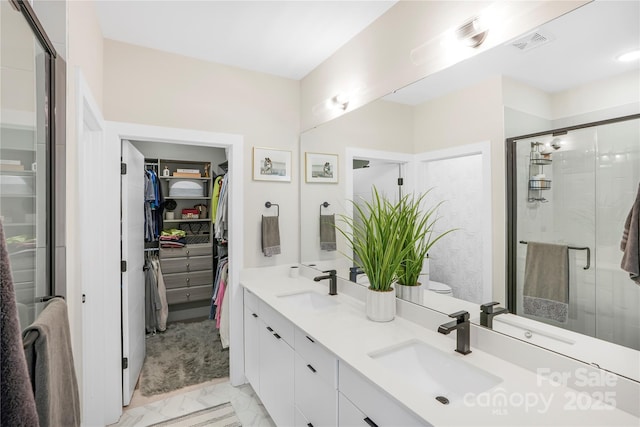 full bathroom featuring marble finish floor, a spacious closet, visible vents, and a sink