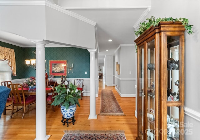 hallway with hardwood / wood-style flooring, ornamental molding, and ornate columns