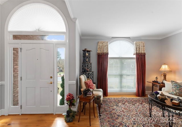 entrance foyer with ornamental molding and light hardwood / wood-style flooring