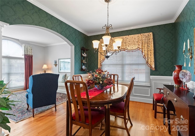 dining area with hardwood / wood-style flooring, ornamental molding, and a chandelier