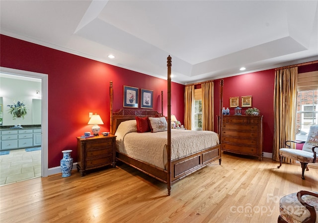 bedroom featuring multiple windows, light hardwood / wood-style floors, and a tray ceiling