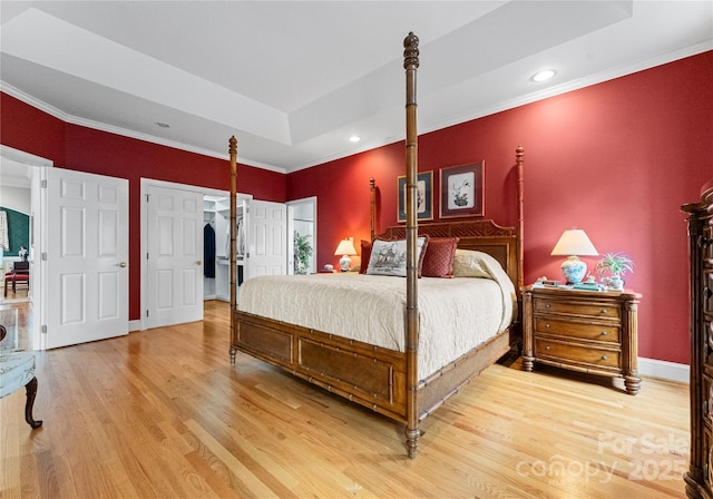 bedroom with hardwood / wood-style flooring, ornamental molding, and a raised ceiling