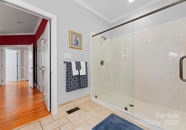 bathroom with crown molding, a shower with shower door, and wood-type flooring