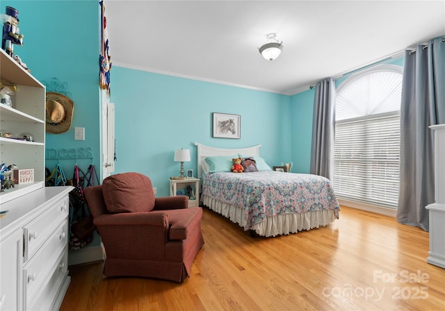 bedroom featuring ornamental molding and light hardwood / wood-style floors