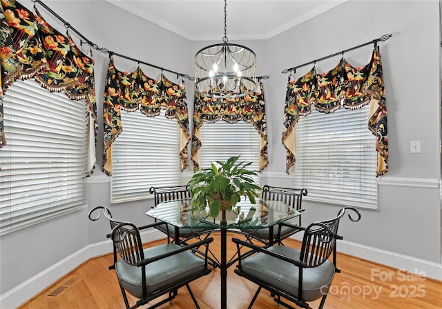 dining area with crown molding, hardwood / wood-style floors, and a notable chandelier