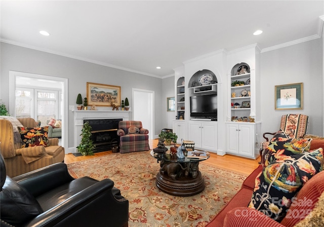 living room with a premium fireplace, ornamental molding, and light wood-type flooring