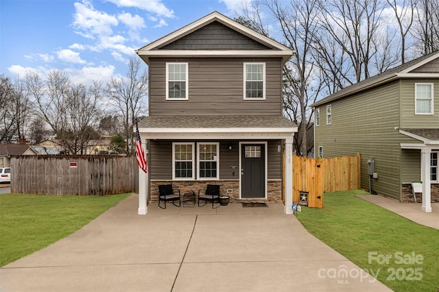 view of front of property featuring stone siding, a front yard, fence, and a gate