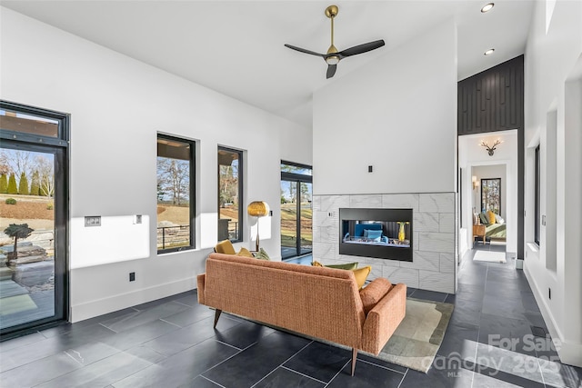 living room with a tiled fireplace, high vaulted ceiling, and ceiling fan