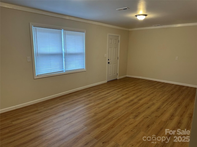 unfurnished room featuring wood-type flooring and crown molding