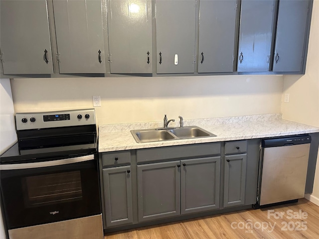 kitchen featuring appliances with stainless steel finishes, sink, gray cabinetry, and light hardwood / wood-style floors