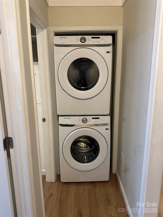 laundry area featuring stacked washer and clothes dryer and hardwood / wood-style floors