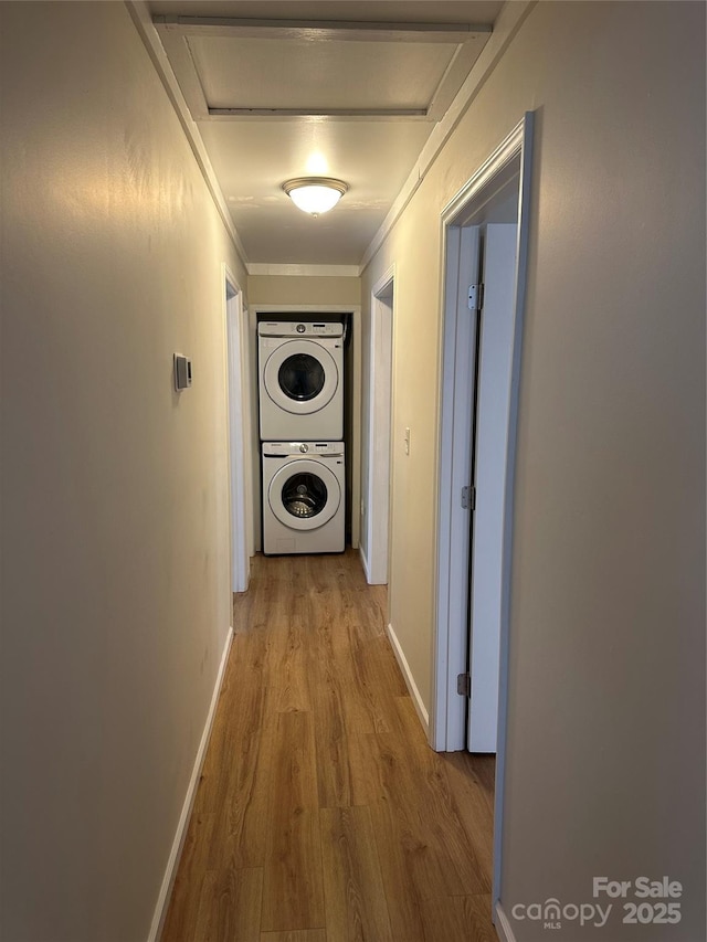 corridor with ornamental molding, light hardwood / wood-style floors, and stacked washing maching and dryer