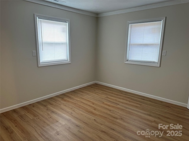 unfurnished room featuring ornamental molding and light hardwood / wood-style floors