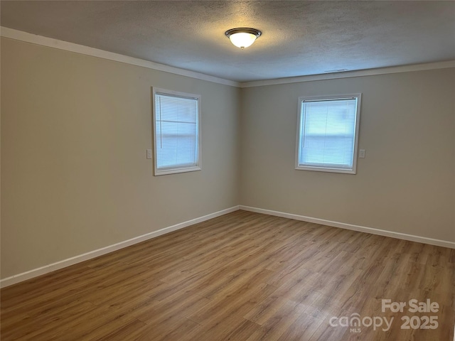 spare room featuring ornamental molding, light hardwood / wood-style flooring, and a textured ceiling