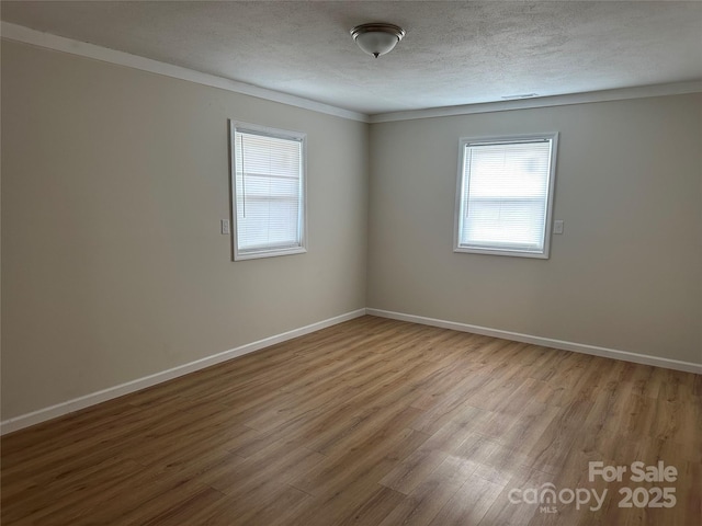 empty room with a healthy amount of sunlight, a textured ceiling, and light hardwood / wood-style flooring