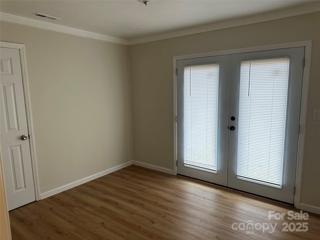 entryway featuring wood-type flooring, ornamental molding, and french doors