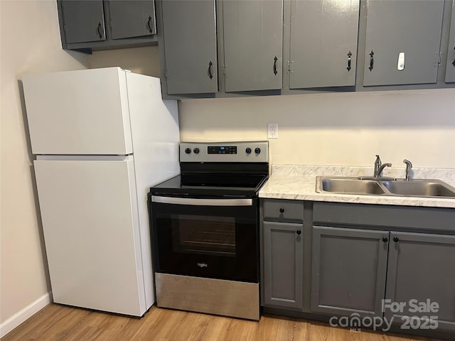 kitchen with white refrigerator, sink, stainless steel range with electric cooktop, and gray cabinetry