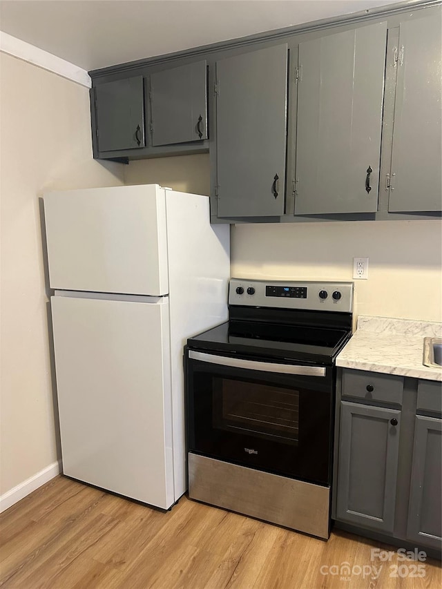 kitchen with white refrigerator, stainless steel electric stove, light hardwood / wood-style flooring, and gray cabinetry