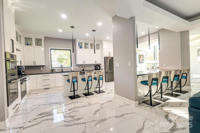 kitchen with pendant lighting, a kitchen bar, white cabinets, and appliances with stainless steel finishes