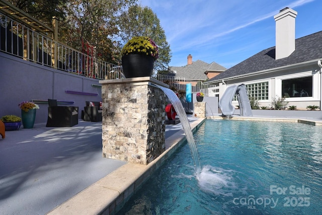 view of swimming pool with pool water feature, a water slide, and a patio