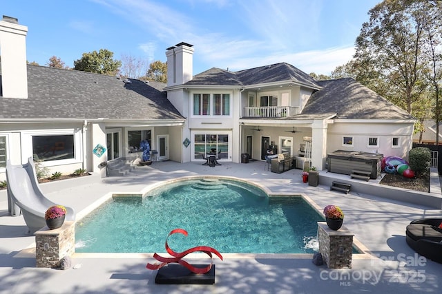 back of property featuring a swimming pool with hot tub, a balcony, a patio, and ceiling fan