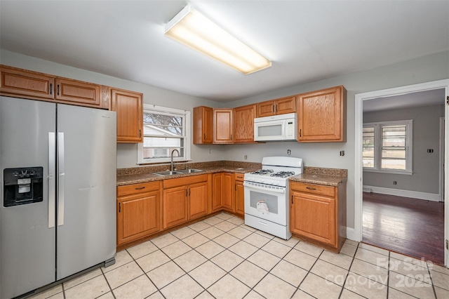 kitchen with sink, light tile patterned floors, and white appliances