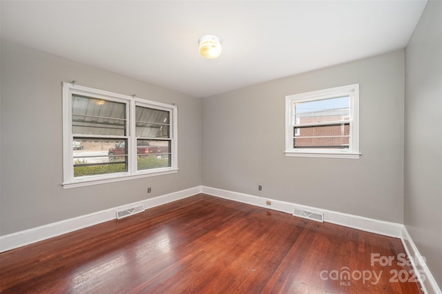 spare room featuring plenty of natural light and dark hardwood / wood-style flooring